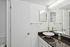 Sleek modern bathroom with elegant vessel sink and glossy black countertop, complemented by bright lighting and a large mirror.