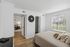 Bright and cozy bedroom with a view of a lush garden, featuring elegant decor, plush pillows, and natural light pouring through large windows.