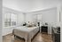 Bright and cozy bedroom with large windows, modern furnishings, and elegant wooden flooring, creating an inviting and restful atmosphere.