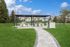 Charming outdoor pavilion with modern seating and BBQ grill set on lush green lawns, ideal for gatherings.