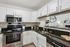 Modern kitchen with sleek stainless steel appliances, white cabinetry, and elegant black granite countertops.