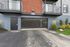 Modern apartment exterior with sleek balcony and secure parking entrance, surrounded by well-maintained landscaping.