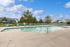 Inviting outdoor pool area with sun loungers and lush green surroundings under a bright blue sky.