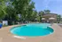 Inviting outdoor pool area with sun loungers and umbrellas surrounded by lush greenery, perfect for relaxation and leisure.
