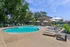 Inviting pool area with sun loungers and umbrellas, surrounded by lush greenery and open blue skies.