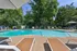 Inviting outdoor swimming pool surrounded by lush greenery, featuring comfortable lounge chairs and shade umbrellas for relaxation.