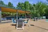 Inviting outdoor lounge area with stylish seating under a modern wooden pergola, surrounded by lush greenery.