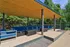 Inviting outdoor lounge with modern blue seating under a stylish wooden pergola, set in a lush garden backdrop.