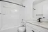 Modern bathroom featuring sleek white bathtub, stylish granite countertop, and elegant black fixtures.