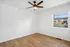 Bright and airy room with elegant ceiling fan and large window overlooking a charming neighborhood.