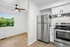Modern kitchen with sleek stainless steel appliances, bright wooden flooring, and ample natural light from a large window.