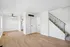 Inviting apartment interior featuring sleek wooden flooring, a modern ceiling fan, and stylish staircase adjacent to kitchen access.