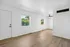 Bright and airy living area with elegant wood flooring, modern ceiling fan, and large windows offering scenic views.