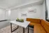 Chic dining nook with a modern marble top table, cozy orange tufted bench seating, and stylish wall art, offering an inviting space for meals and gatherings.