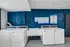 Modern laundry room with high-efficiency washers and dryers against a stylish dark blue wall, offering convenient and eco-friendly amenities.