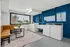 Bright, modern laundry room with cozy seating area, featuring top-of-the-line machines and large window view.