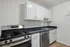 Modern kitchen with sleek white cabinetry, stainless steel appliances, and elegant black countertops, offering a stylish and functional space.
