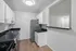 Modern kitchen with sleek white cabinets, glossy black countertops, stainless steel appliances, and wood flooring, creating a sleek and inviting space.