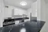 Modern kitchen with sleek black countertops, stainless steel stove, and white cabinetry offering a fresh, elegant ambiance.
