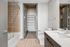 Elegant bathroom with modern fixtures, featuring a sleek vanity, spacious walk-in closet, and relaxing bathtub.