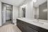 Elegant modern bathroom featuring a sleek dual-sink vanity, bright lighting fixtures, and an adjoining spacious walk-in closet.