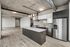 Sleek and modern open-concept kitchen with stainless steel appliances, large island, and industrial-style ceiling in a spacious apartment.