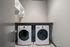 Modern laundry room with sleek washer and dryer, ample shelving, and contemporary design.