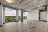 Contemporary open-concept apartment with stunning floor-to-ceiling windows offering a breathtaking city view, featuring sleek exposed ceilings and modern flooring.