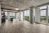 Sleek open-concept apartment with panoramic floor-to-ceiling windows, modern kitchen, and urban cityscape views.