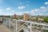 Stunning cityscape view from a modern apartment balcony, showcasing vibrant urban architecture and a clear blue sky.