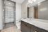 Modern bathroom featuring a sleek vanity, large mirror, and spacious walk-in closet with ample shelving.