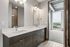Modern bathroom with dual sinks and sleek vanity, opening to a room with a stunning city view from a high-rise apartment.