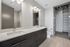 Modern bathroom featuring sleek dual sinks, elegant lighting, and a spacious walk-in closet.