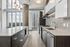 Sleek modern kitchen with expansive windows, showcasing panoramic city views, elegant fixtures, and streamlined cabinets.