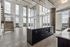 Sophisticated open-plan loft with expansive floor-to-ceiling windows, modern industrial finishes, and a sleek kitchen island.
