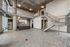 Modern urban loft with high ceilings, exposed concrete, and a sleek kitchen featuring stainless steel appliances and upscale lighting.