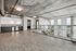 Modern industrial loft with sleek open-plan living area, expansive windows, and stylish kitchen, offering stunning cityscape views.