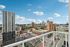 Stunning cityscape view from modern apartment balcony featuring a vibrant urban skyline and clear blue skies.
