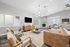 Elegant living room featuring modern decor, a comfortable leather sofa, stylish armchairs, and a cozy fireplace, illuminated by a chic chandelier.