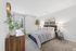 Inviting bedroom with a plush bed, elegant decor, and large window offering scenic views, perfect for relaxation.