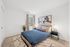 Modern bedroom with elegant decor, featuring a comfortable bed, stylish artwork, and natural lighting through large windows.