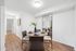 Inviting dining area in a modern apartment, featuring a round wooden table set with elegant dishes, complemented by bright lighting and a stylish wall mirror.