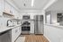 Modern kitchen with sleek stainless steel appliances, elegant white cabinetry, and rich hardwood floors, offering a stylish and functional space.