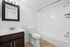 Modern bathroom with bright white tiles, elegant mirror, and sleek fixtures offering a refreshing and clean ambiance.