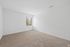 Bright and airy bedroom with soft carpet flooring, large window offering natural light and serene outdoor views, ideal for a cozy retreat.