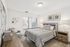 Bright and modern bedroom with cozy decor, featuring a large window, stylish bed with striped bedding, and elegant wall art.