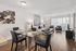 Bright, modern living and dining area featuring sleek glass dining table, plush seating, and elegant decor with abundant natural light from large windows.