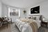 Bright and serene bedroom featuring a plush bed, modern decor, and a cozy workspace overlooking nature.