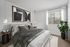 Sophisticated bedroom with modern decor, featuring a plush bed, stylish artwork, and large window for natural light.