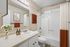 Elegant bathroom with modern fixtures, bright vanity, decorative artwork, and warm accents creating a cozy atmosphere.